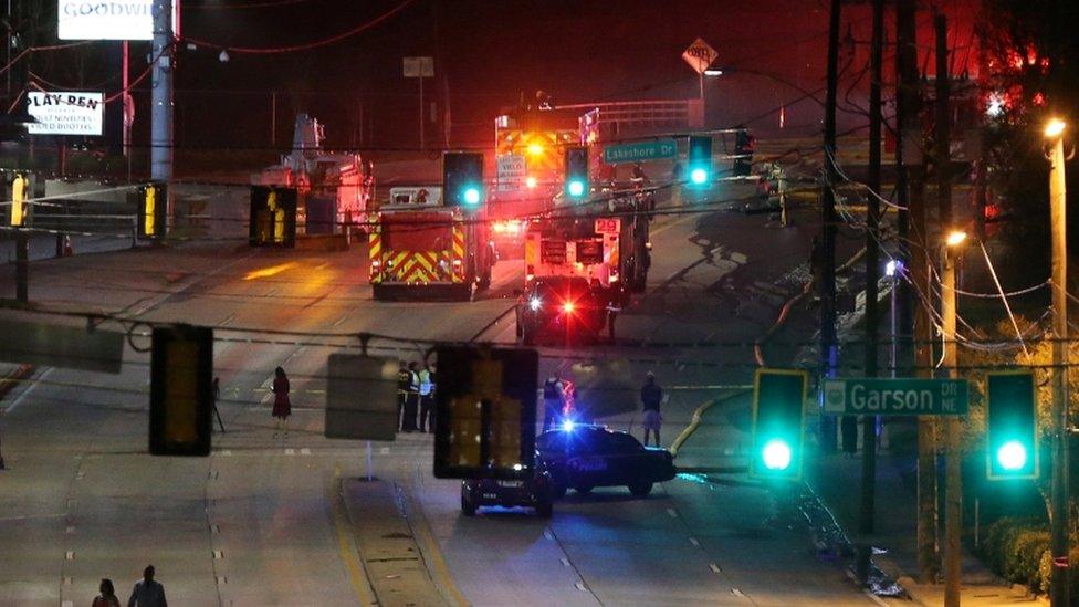 People make their way away from the bridge fire on Piedmont Road as emergency personnel work the scene of a bridge collapse at I-85 in Atlanta, Georgia