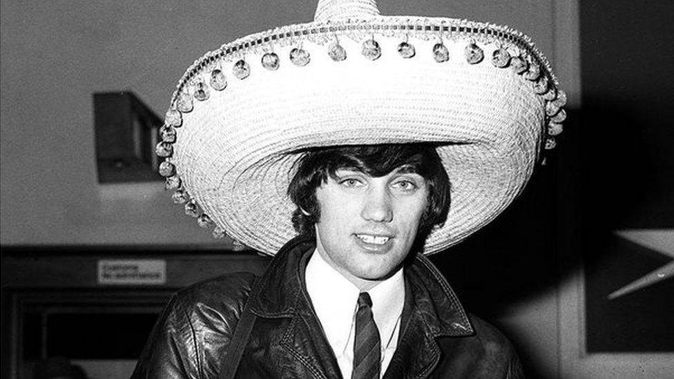 Manchester United footballer George Best wearing a souvenir sombrero on his return to London airport following United's defeat of Benfica 5-1 in the second leg of the European Cup quarter final football match. Best scored United's first two goals. 11/03/1966