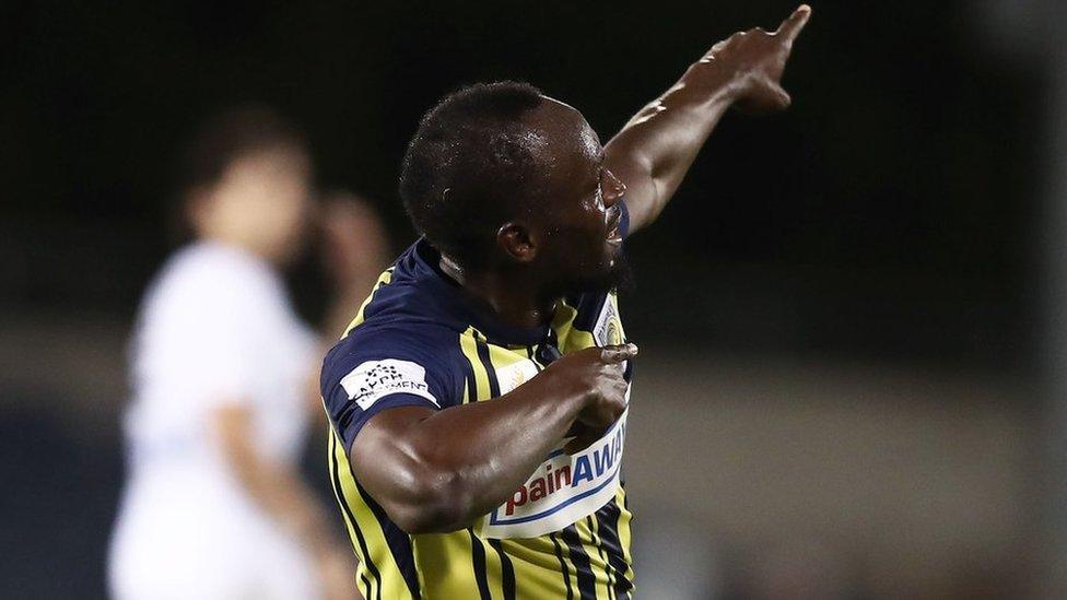 Usain Bolt with his back to camera poses with his trademark lightning bolt celebration