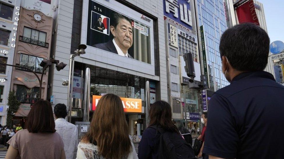 People watch a television announcement on Abe's resignation