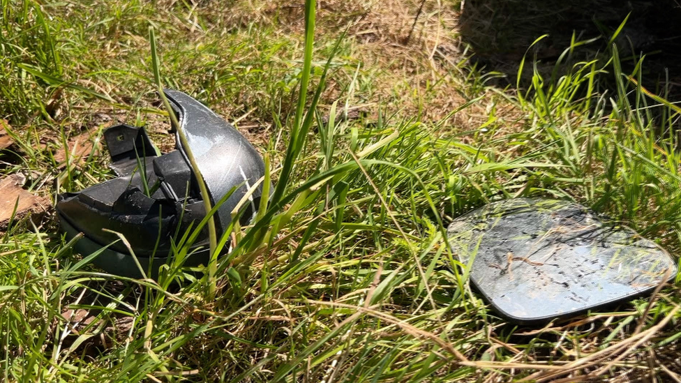 A broken car wind mirror lies in a grass verge