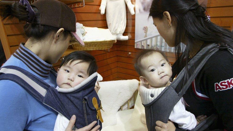 Two mothers carrying their babies while at a baby fair