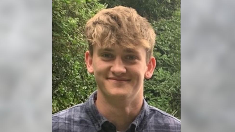 A young man with brown hair smiling at the camera