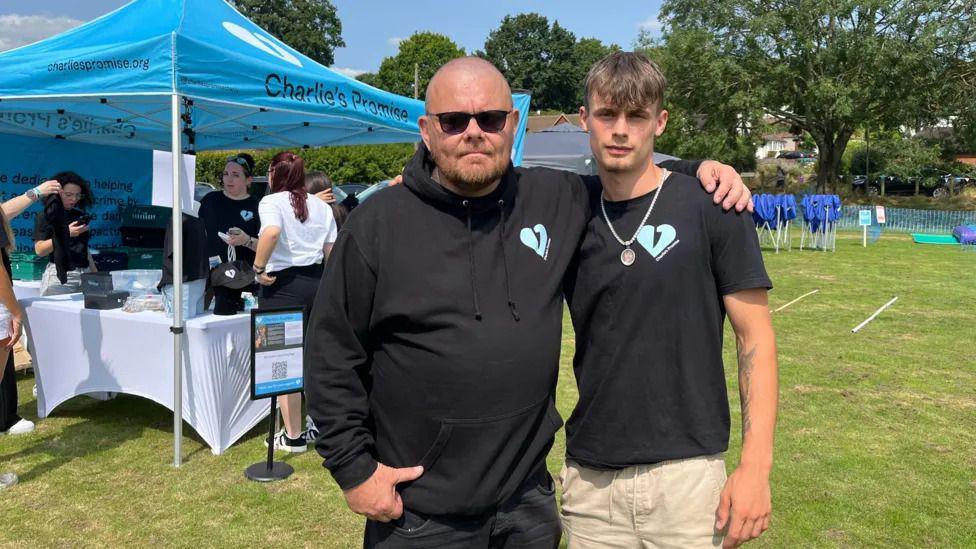 Two men dressed in black stood in a field