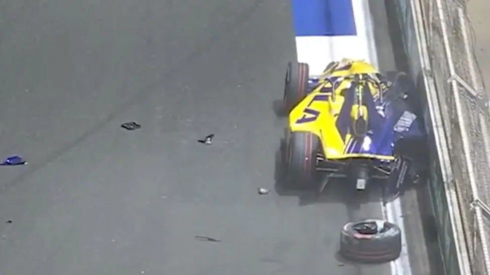 View of Izzy Hammond's crash from the rear. The car's right-hand side is up against a barrier and one of its tyres is on the road behind the vehicle.