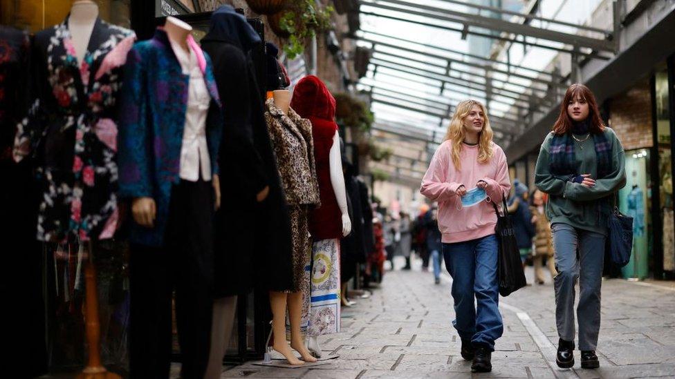 Shoppers walk past stalls in Camden market