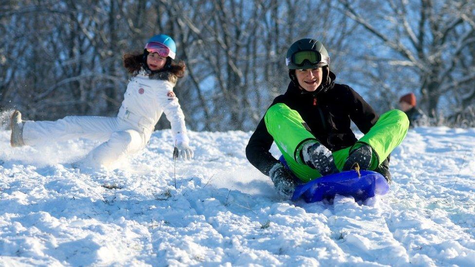 Children in Belgium playing in the snow, one on a sled