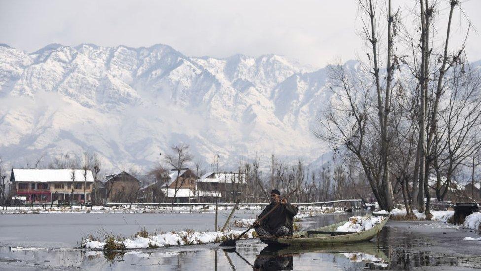 A Kashmiri boatman rows his boat on Dal Lake after fresh snowfall in Srinagar.