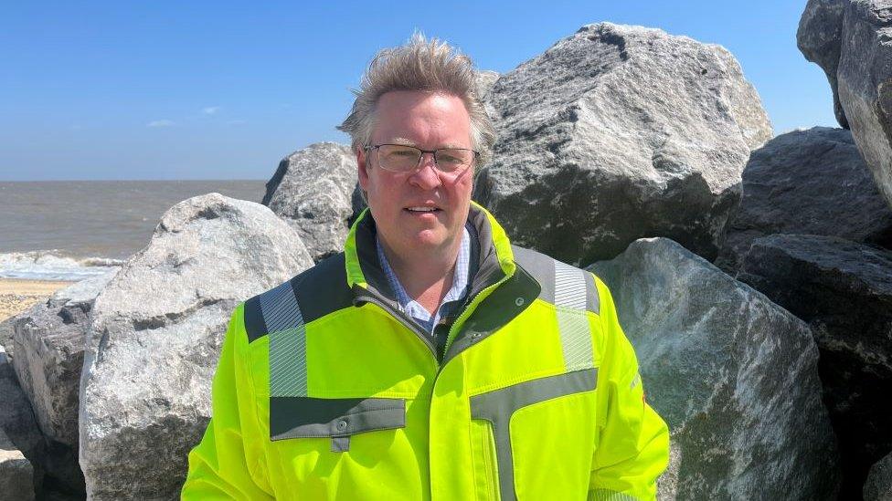 Edward Vere Nicoll standing in front of some huge boulders on Benacre sluice.