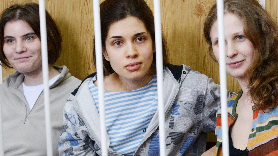 Members of the all-girl punk band 'Pussy Riot' Nadezhda Tolokonnikova (C), Maria Alyokhina (R) and Yekaterina Samutsevich (L), sit behind bars during a court hearing in Moscow in July 2012