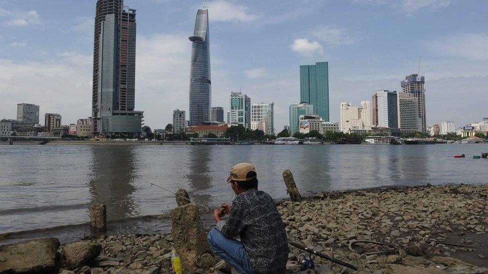 Ho Chi Minh City skyline with man fishing in foreground