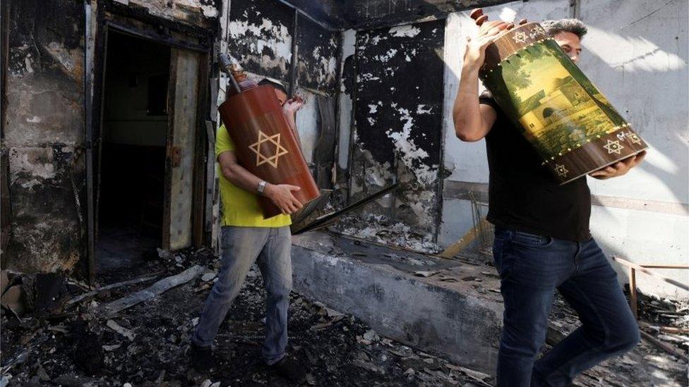 Torah scrolls, Jewish holy scriptures, are removed from a synagogue in the city of Lod, Israel (May 12, 2021)