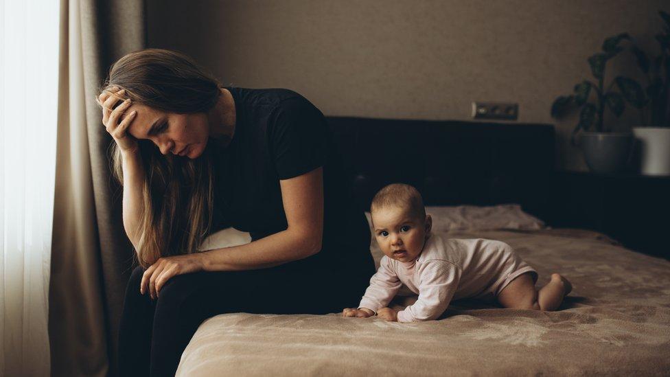 Woman sitting on bed with a baby