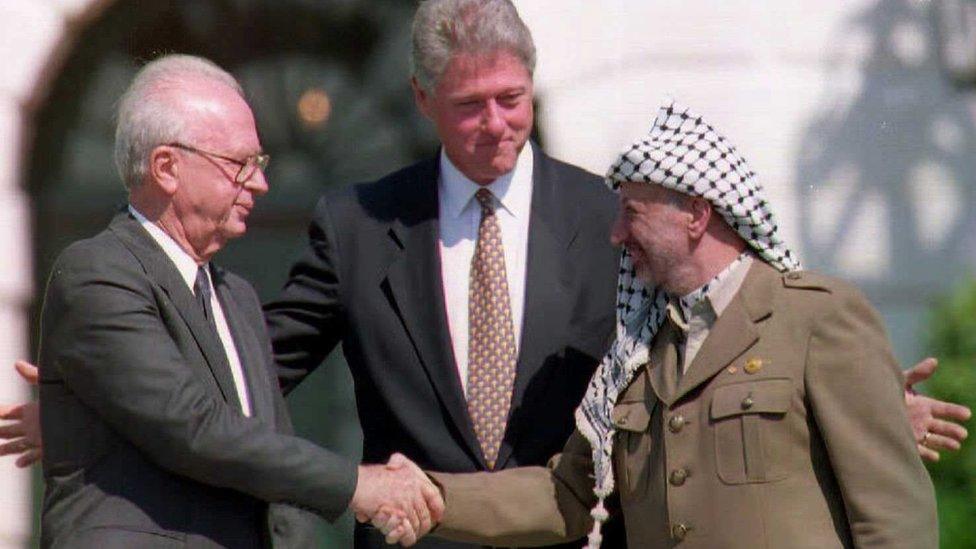 Bill Clinton standing between Palestinian leader Yasser Arafat as he shakes hands with Israeli Prime Minister Yitzhak Rabin after signing the Middle East Peace Accord, on 13 September 1993