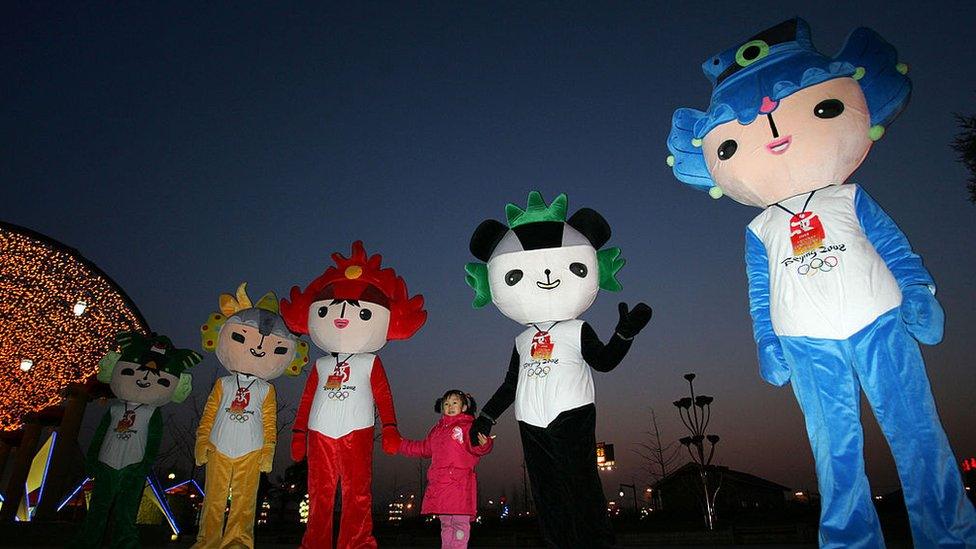 Five mascots - one is blue, one is green, one is red, one is yellow and one looks like a panda