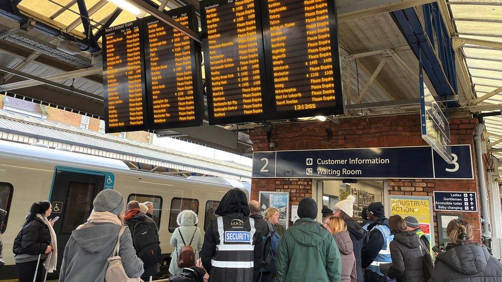 Passengers standing under train departure board