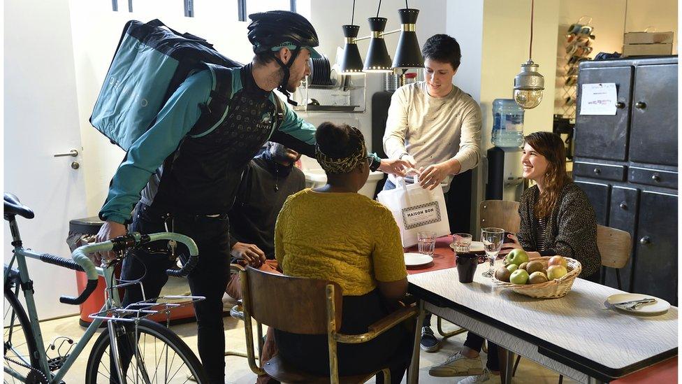 Deliveroo driver presents customers with a meal