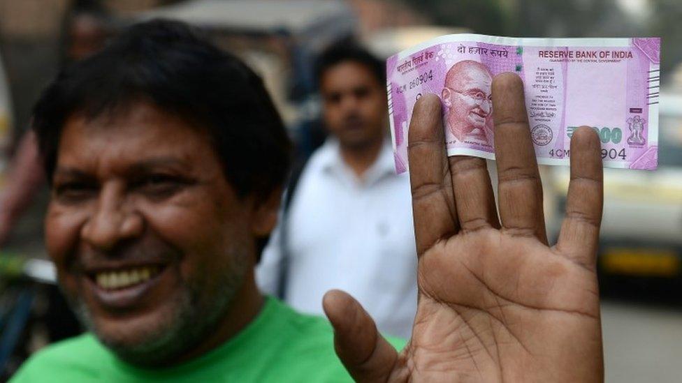 An Indian man displays a new 2000 rupee note after exchanging his old 500 and 1000 rupee notes at a bank in New Delhi on November 10, 2016.