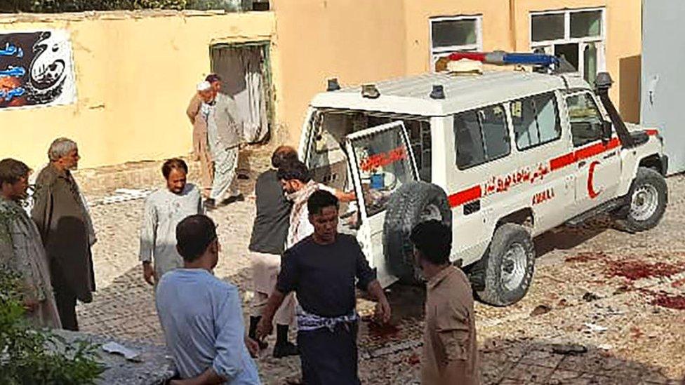 Afghan men stand next to an ambulance after a bomb attack at a mosque in Kunduz, Afghanistan, 8 October 2021