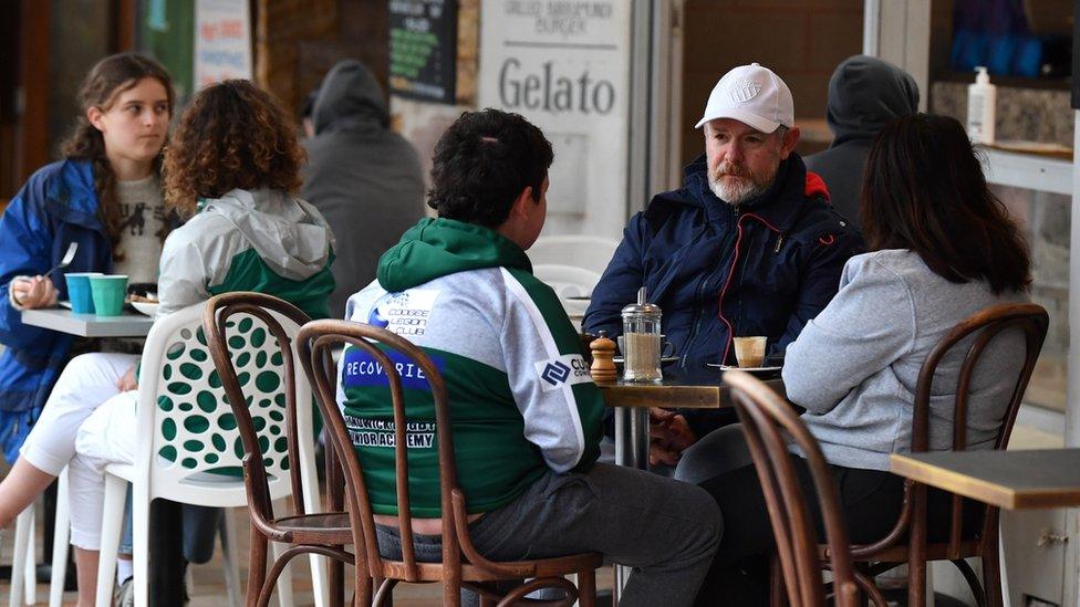 People sit at a beachside cafe in Bronte, Sydney on the first day of the city's reopening