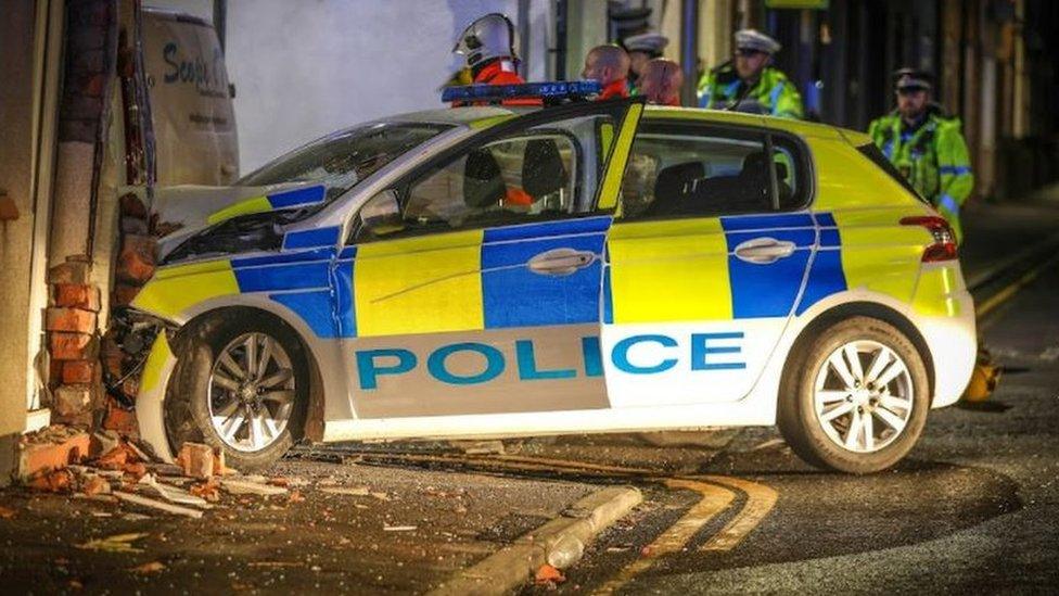 Police car embedded in house