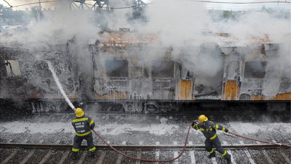 Firefighters douse a train carriage to put out a fire