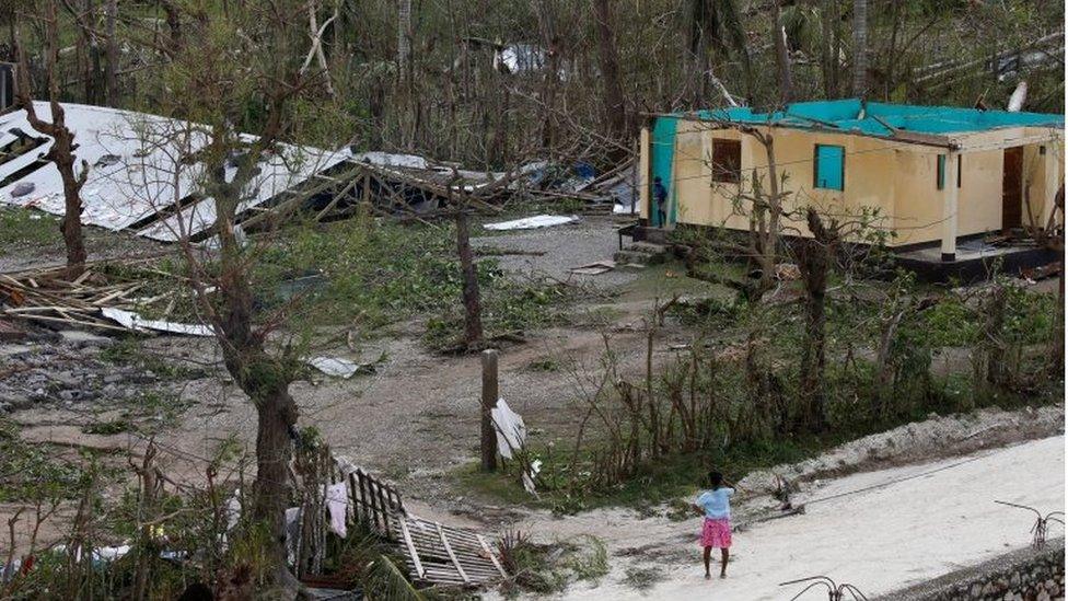 A woman stands in front of a destroyed house after Hurricane Matthew passes Jeremie, Haiti, on 5 October 2016.