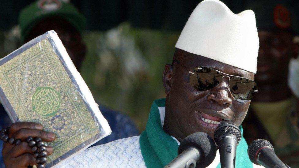 President Jammeh holds up a Koran while speaking into a microphone