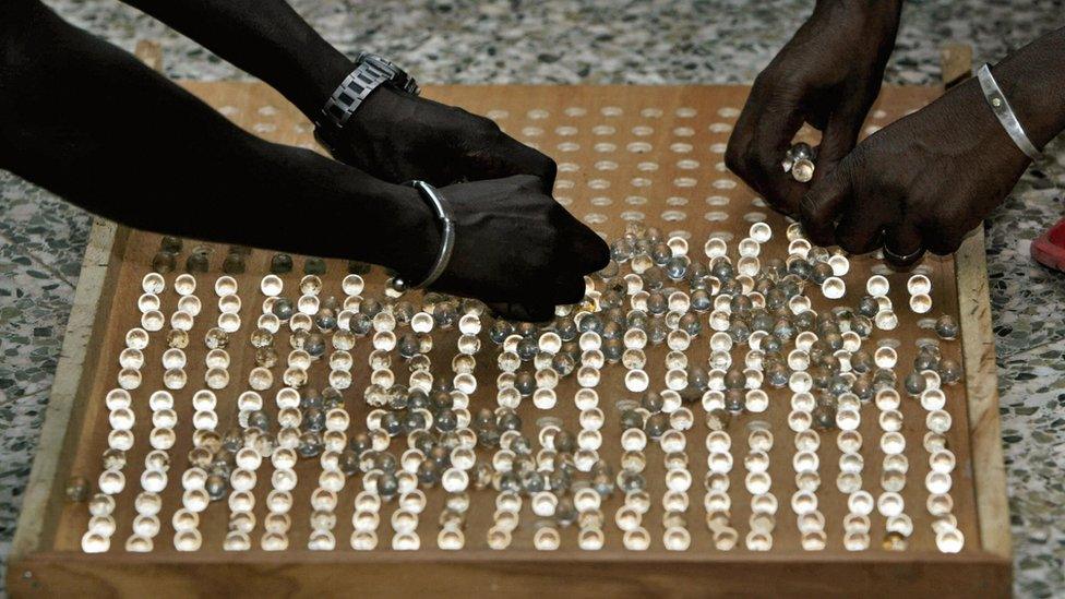 Two people arranging marbles on a board.