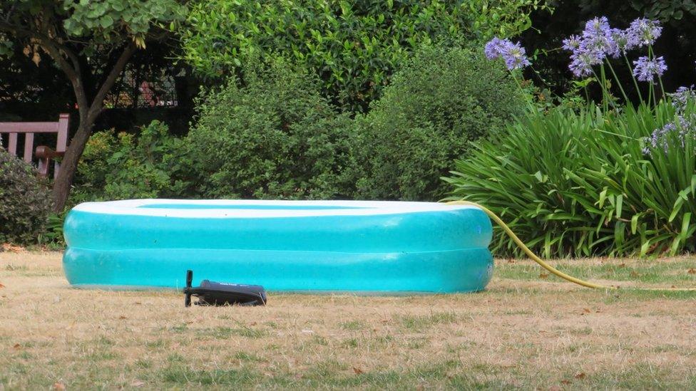 Blue paddling pool filled with yellow hose