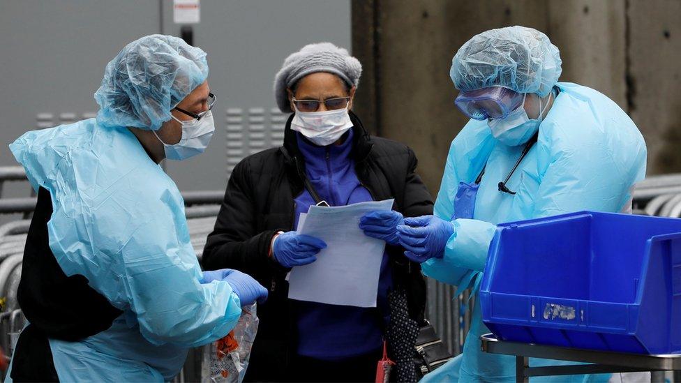 Hospital workers are seen near a tent erected to test for the coronavirus disease at the Brooklyn Hospital Center in Brooklyn