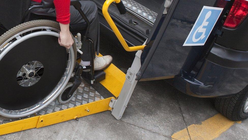 A person in a wheelchair going into a taxi