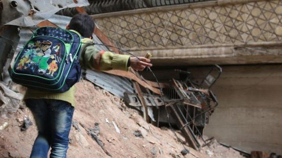 A child navigates through rubble and barbed wire in Aleppo (12 February 2016)