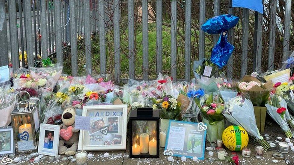 Floral tributes with candles and football t-shirts, balloons etc tied to railings