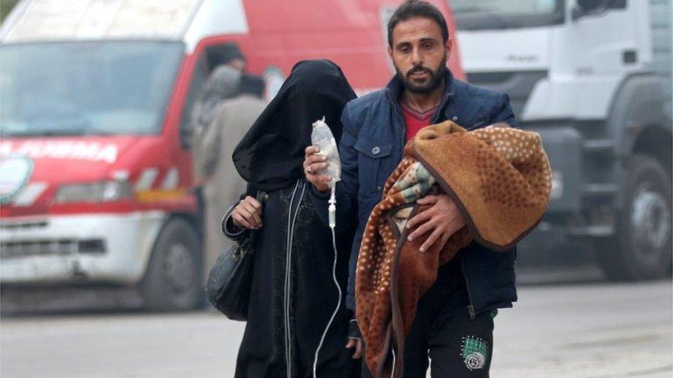 A man carries a child with an IV drip as he flees deeper into the remaining rebel-held areas of Aleppo, Syria December 12, 2016.