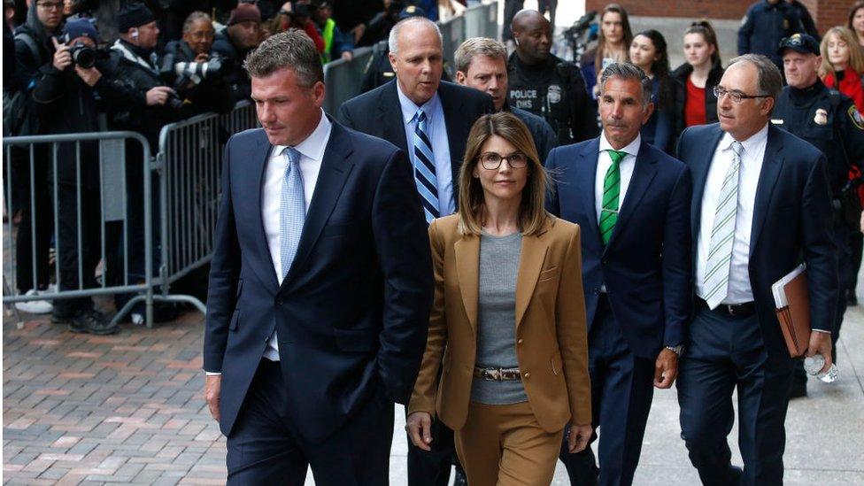 Actress Lori Loughlin, center in tan, and her husband Mossimo Giannulli, in green tie behind her, leave the John Joseph Moakley United States Courthouse in Boston on April 3, 2019