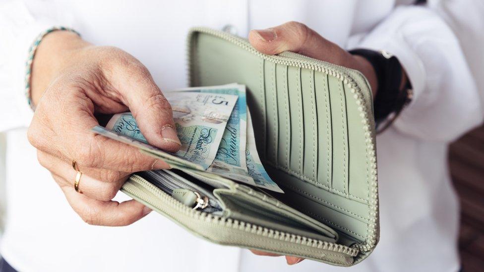 Woman holding wallet with money inside