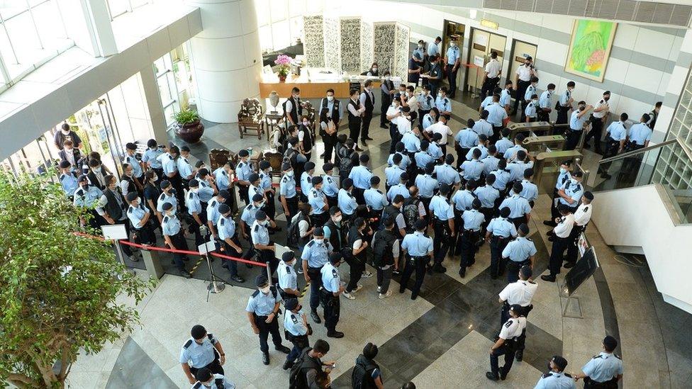 A handout photo made available by Apple Daily shows police officers arriving at the office of Next Media