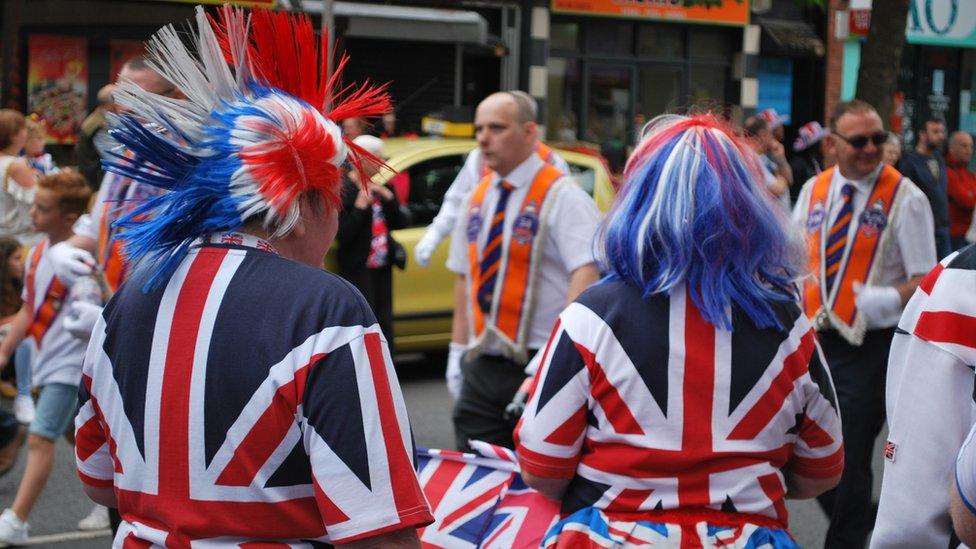 Women dressed in union jacks watching the Twelfth of July parade