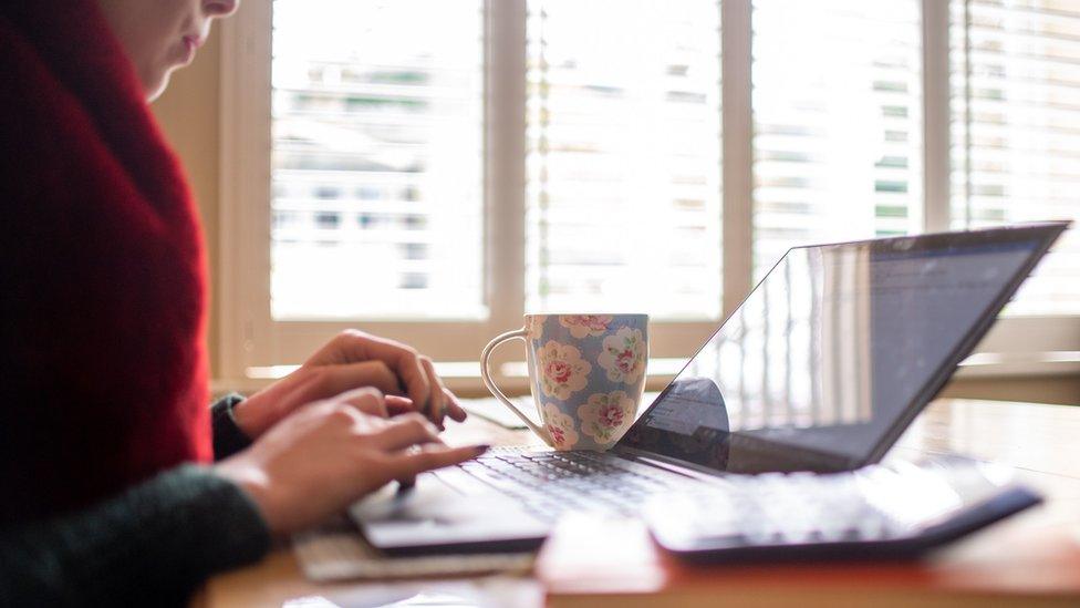 a woman using a laptop on a dining room table