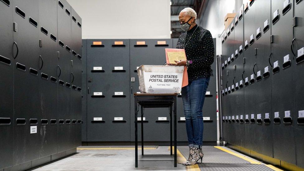 A woman surrounded by filing cabinets looking through ballots in Georgia.