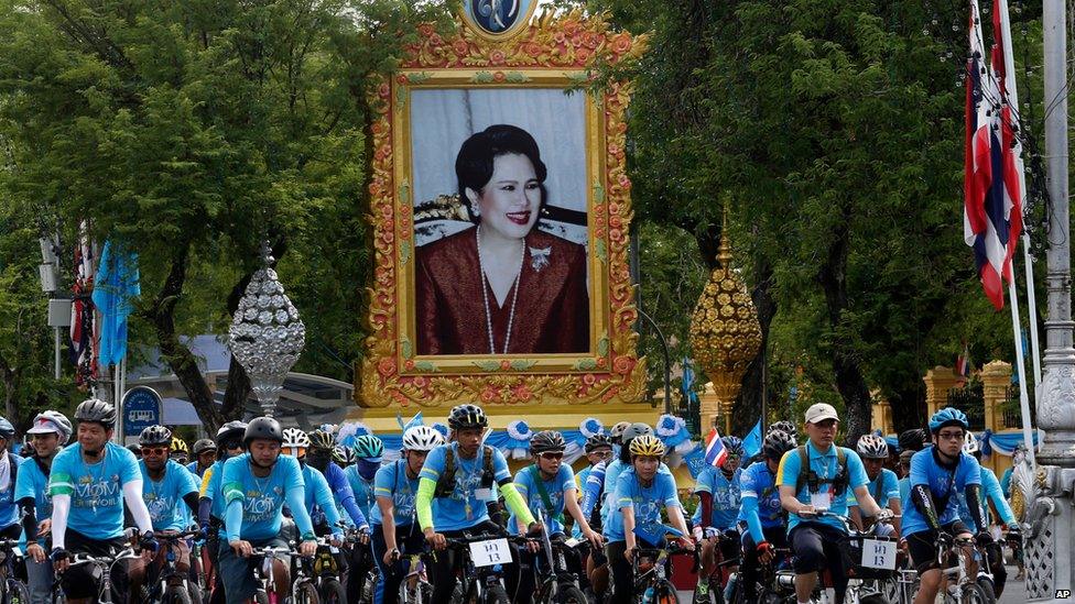 Cyclists pass by a portrait of Queen Sirikit in Bangkok, Thailand, on Sunday