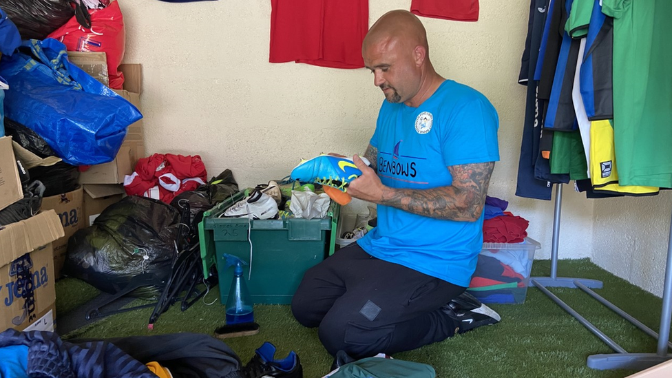 Luke Riggs cleans up a pair of donated football boots