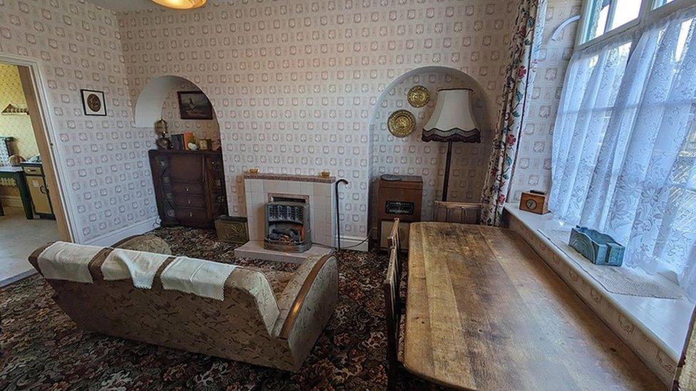 A replica 1950s front room with a sofa, fireplace and table