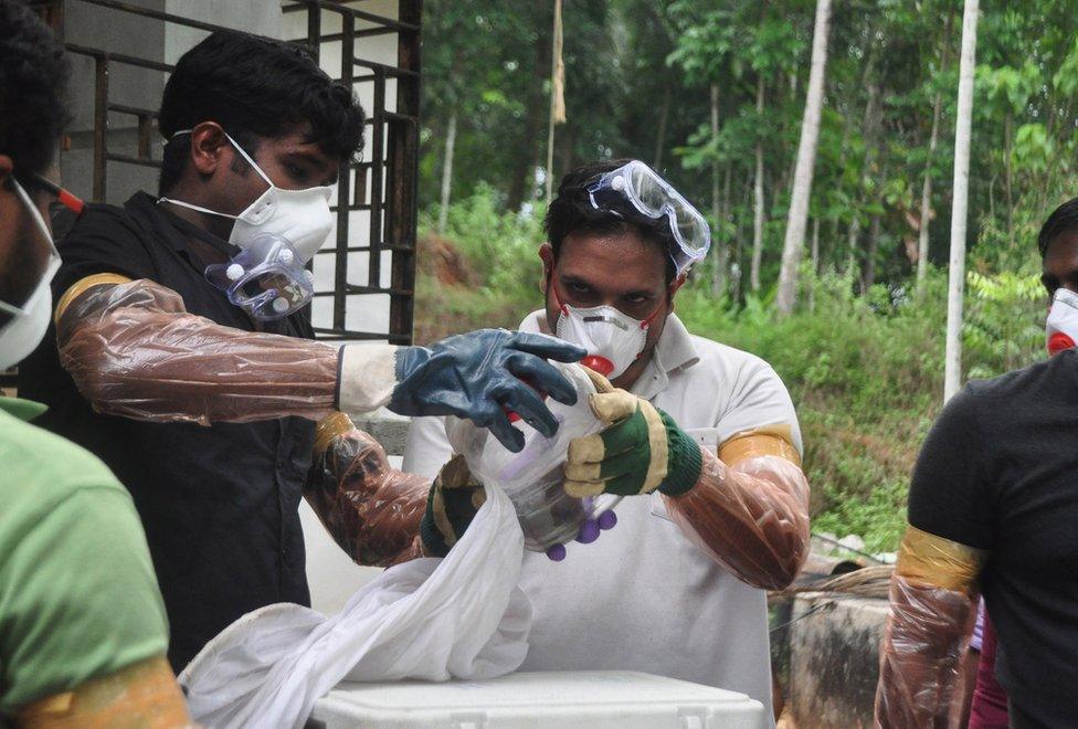 Animal Husbandry department and Forest officials deposit a bat into a container after catching it inside a well at Changaroth in Kozhikode in the Indian state of Kerala on May 21, 2018.