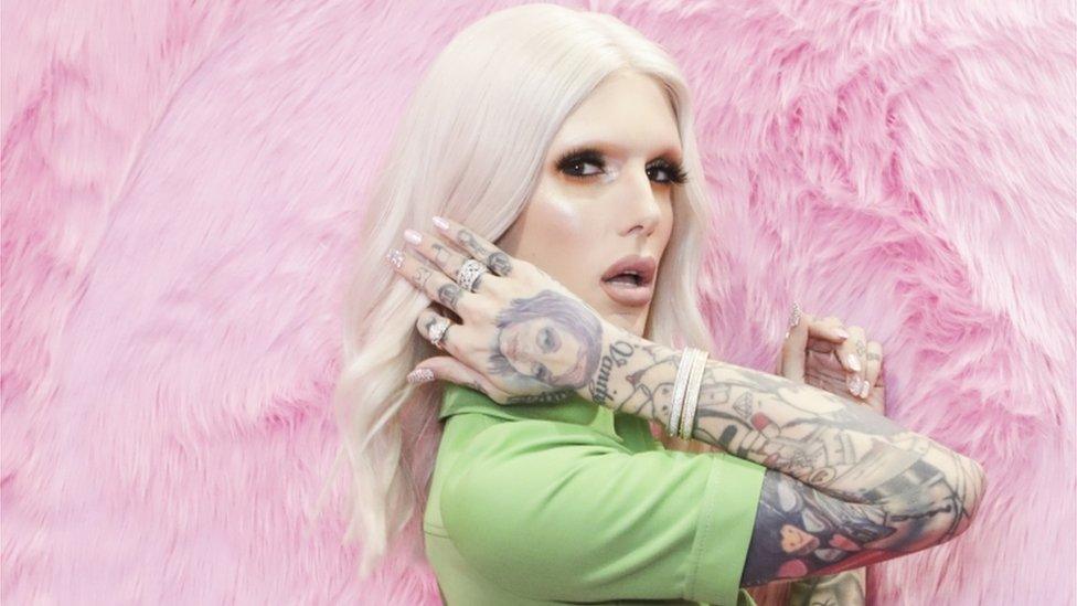 Jeffree Star standing against a pink fluffy background