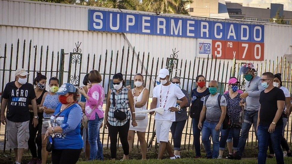 People queue to buy products with US dollars at a supermarket in Havana