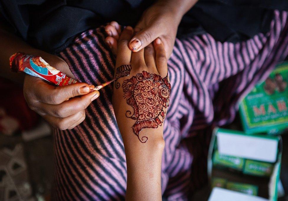 Hand being painted with henna