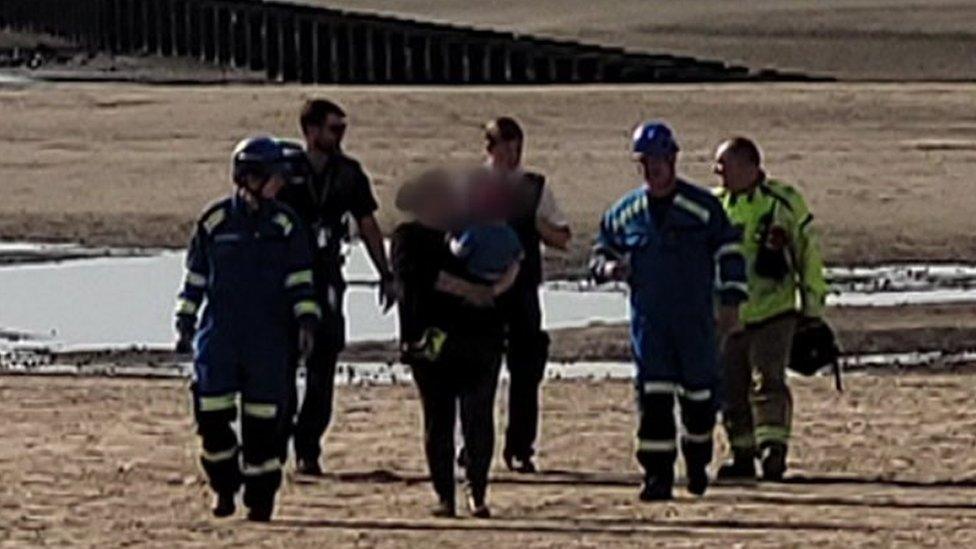 mum and baby walk away with emergency service workers