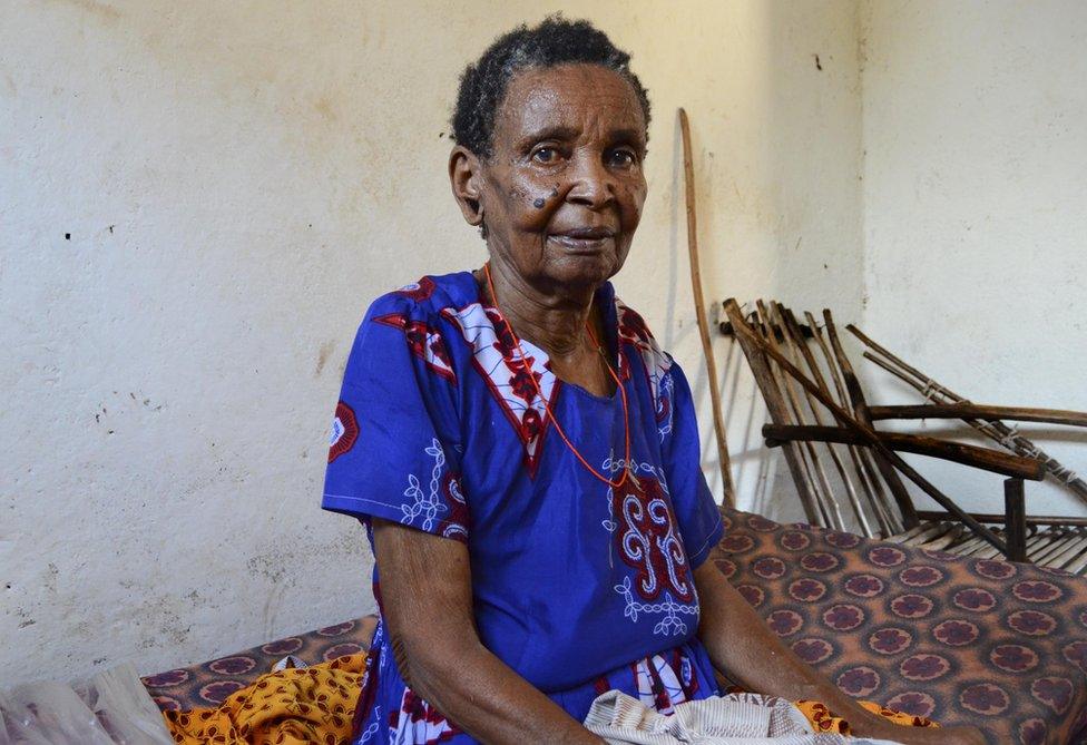 A woman sits on her bed